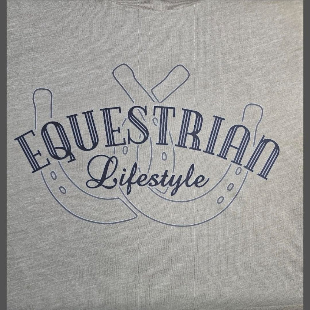 A close-up of a light heather gray t-shirt featuring a navy blue graphic print of two horseshoes with the words 'EQUESTRIAN Lifestyle' written across the front.