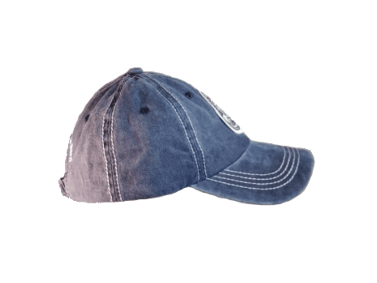 A washed blue denim baseball cap with white contrast stitching and a small white embroidered logo on the side, shown against a plain white background.