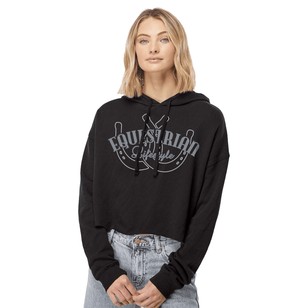 A woman modeling a black cropped hoodie with a gray graphic that reads 'Equestrian Lifestyle' over horseshoes, paired with light-wash jeans against a plain white background.