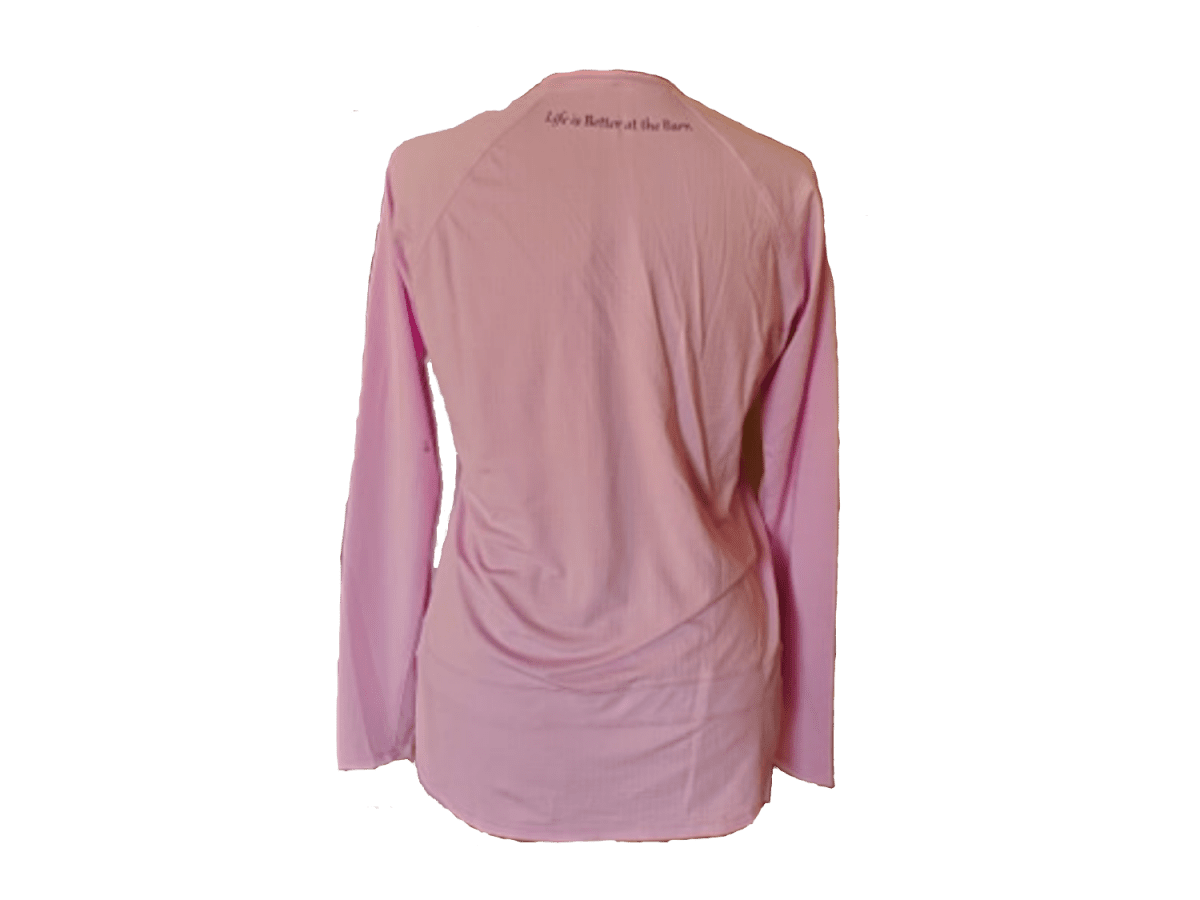 A pink long-sleeve athletic top shown from the back, featuring the printed text 'Life is Better at the barn' across the upper neck, displayed against a solid white background.