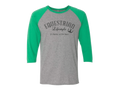 A 3/4 sleeve raglan baseball t-shirt with a heather gray body and bright green sleeves. The front features a black graphic print that reads 'EQUESTRIAN Lifestyle It's Better at the Barn' with a horseshoe symbol.