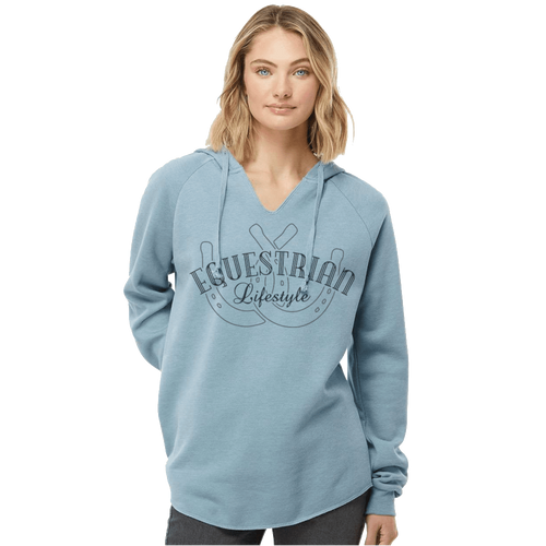 A woman wearing a light blue pullover hoodie with a dark gray graphic on the front that reads 'EQUESTRIAN Lifestyle' with a horseshoe  design, set against a plain white background.