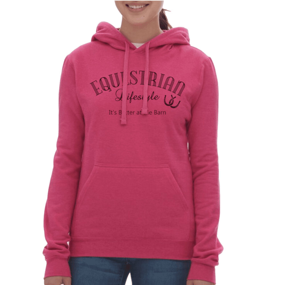 A woman wearing a bright pink pullover hoodie with 'EQUESTRIAN Lifestyle' and 'It's Better at Allie Barn' printed in dark pink on the front, paired with blue jeans against a plain white background.