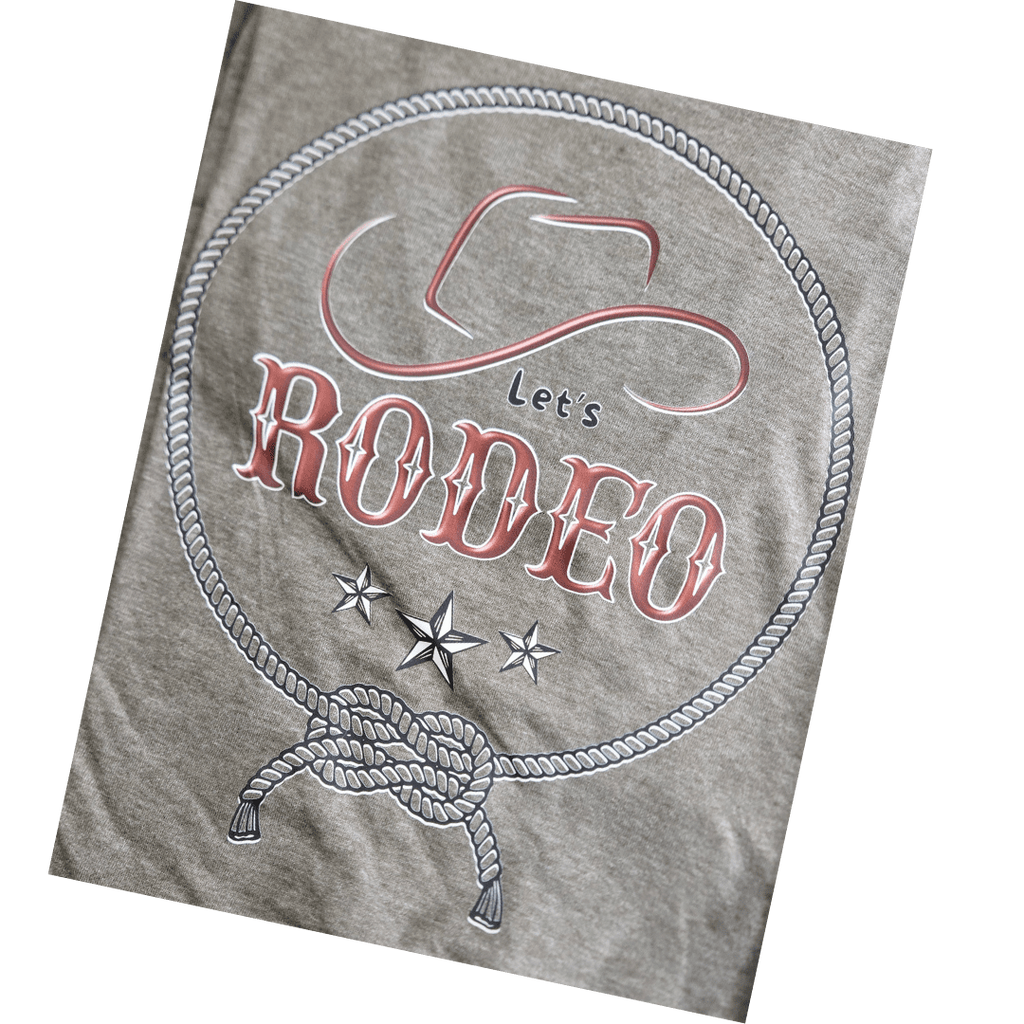 A close-up of a heather gray fabric surface featuring a western-themed graphic with the words 'Let's RODEO,' a cowboy hat outline, rope border, stars, and a tied lasso design.