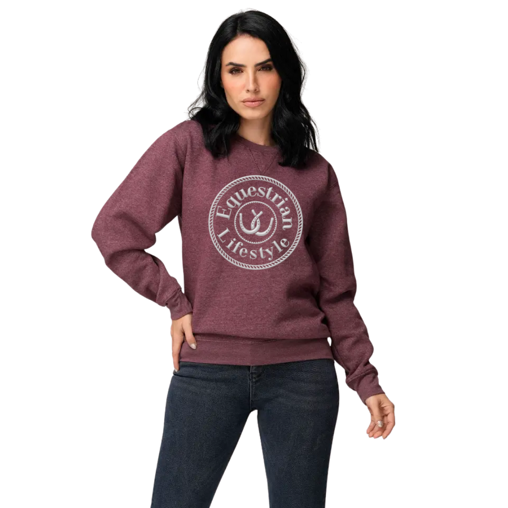 A woman modeling a heathered maroon crewneck sweatshirt with a white circular graphic that reads 'Equestrian Lifestyle' on the chest, paired with dark blue jeans against a plain white background.