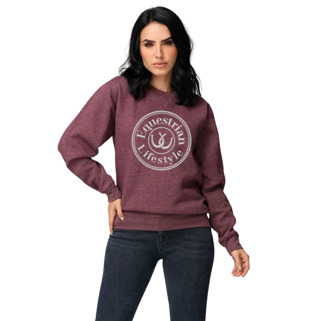A woman modeling a heathered maroon crewneck sweatshirt with a white circular graphic that reads 'Equestrian Lifestyle' on the chest, paired with dark blue jeans against a plain white background.