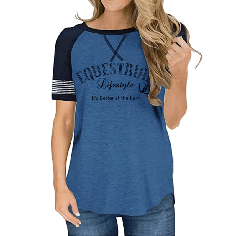A woman wearing a heather blue raglan t-shirt with navy sleeves and a graphic print that reads 'EQUESTRIAL Lifestyle' and 'It's Better at the Barn'.