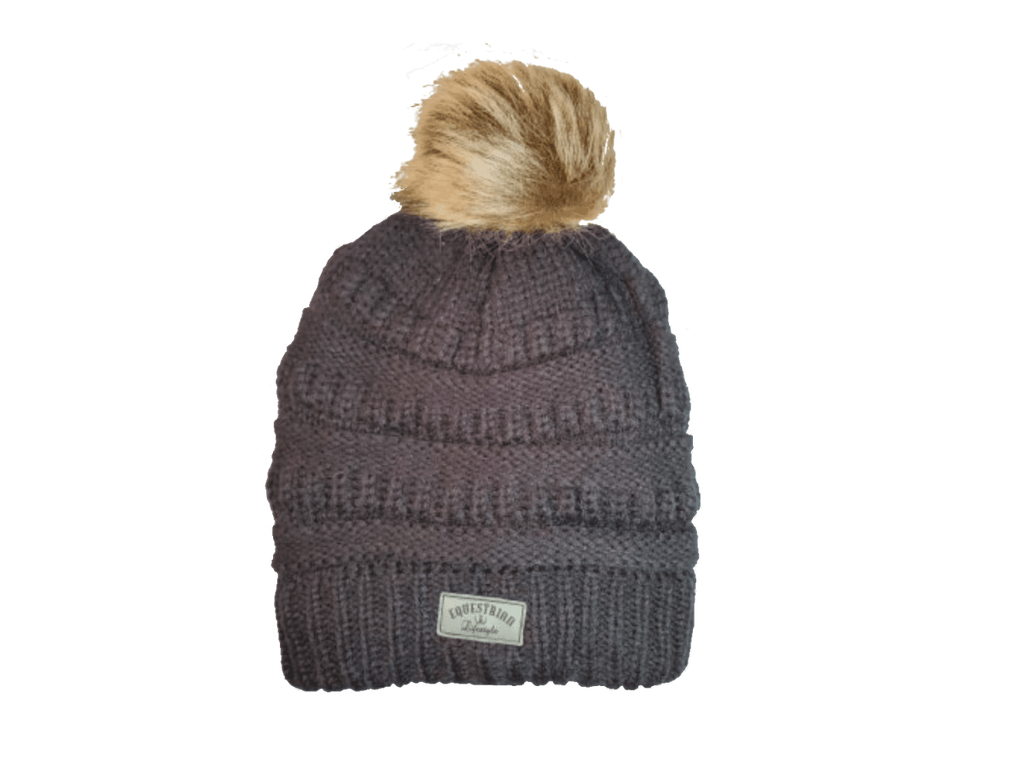 A dark gray ribbed knit beanie hat with a fluffy tan faux-fur pom-pom on top and a small white brand patch on the front cuff. The brand name 'equestrian lifestyle is visible on the patch.